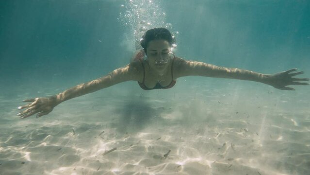Underwater girl swimming in the crystal clear water, wearing red swimsuit, clear emerald sea