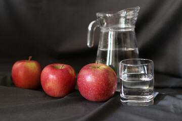still life, a glass of water and ripe apples, a decanter in the background