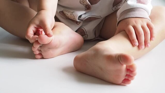 Close up Baby grabbing his feets with hands on white background