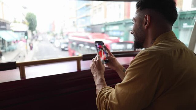 young adult man sitting inside the bus while checking his dating app on his cell phone