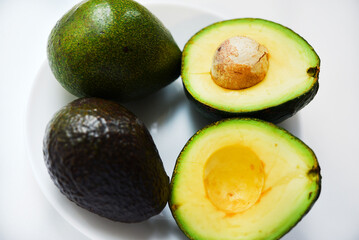 Sliced green avocado on a white background. Pieces of green vegetable on a white plate. Delicious food for a vegan.