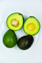 Sliced green avocado on a white background. Pieces of green vegetable on a white plate. Delicious food for a vegan.