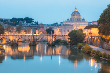 Fototapeta na wymiar Sceninc twilight view of Saint Peter's Basilica at Vatican City and Ponte Vittorio Emanuele II illuminated along the Tiber River on a summer evening in Rome, Italy.