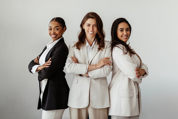 Successful international young businesswomen posing with arms crossed and smiling at camera,...