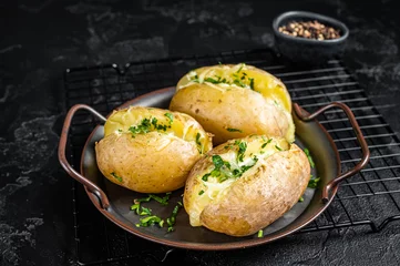 Foto op Aluminium Baked Jacket potatoes with cheese, herbs and butter. Black background. Top view © Vladimir