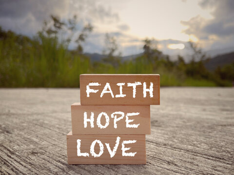 Motivational and inspirational wording. Christianity concept- ‘FAITH, HOPE and LOVE’ words written on wooden blocks. With blurred styled background.