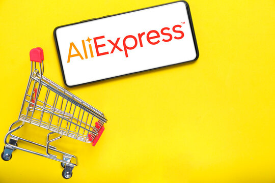 Kostanay, Kazakhstan, August 31, 2023. Smartphone with aliexpress logo,shopping basket yellow background.Concept online shopping.