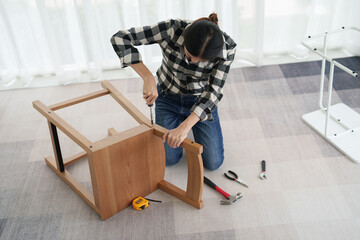 young woman assemble furniture pieces in own home..