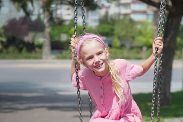 A joyful little one revels in the playground swings at the urban park. 