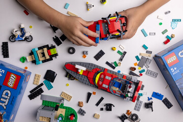 Naklejka premium Riga, Latvia - September 12, 2023: child playing with Lego constructor on the table. building a firefighter car