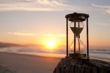 Hourglass on a beach in front of a beautiful sunrise, shallow DOF.