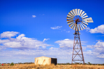 Windmill in Queensland, Australia, with blue sky and fluffy white clouds