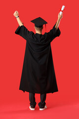 Happy male graduate student with diploma on red background, back view