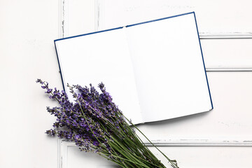 Beautiful lavender flowers and blank book on light wooden background