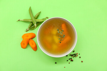 Bowl of tasty vegetable broth on green background