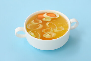 Pot of tasty vegetable broth on blue background