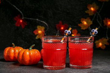 Glasses of delicious cocktail for Halloween and pumpkins on dark background, closeup