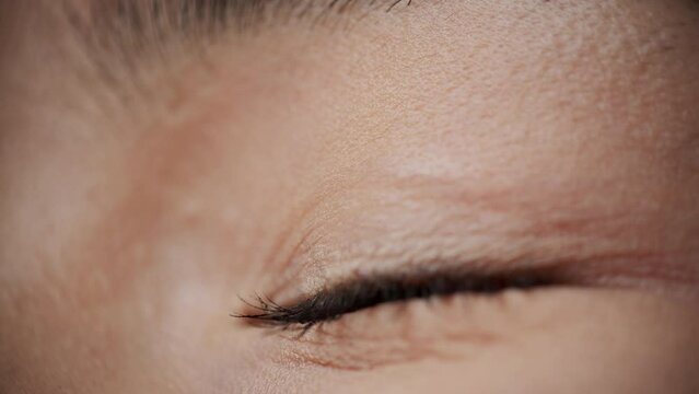 Close-up of the eye of a young asian woman that firstly looking up with confidence and joy and then closing. Concept of vision of the future and hope for the best