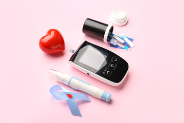 Glucometer, red heart, lancet and blue ribbon on pink background. Diabetes concept