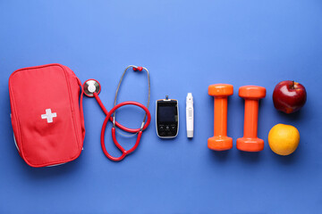 Glucometer, dumbbells, fruits, stethoscope and first aid kit on blue background. Diabetes concept