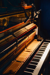 Close up of inside of beautiful upright piano in dramatic light in musician's recording studio