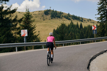 Back view of a female cyclist during a ride. Woman cyclist is wearing cycling kit and a helmet...