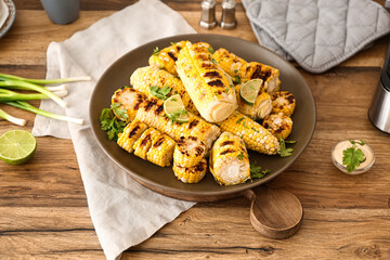 Plate with tasty grilled corn on wooden kitchen counter