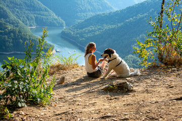 woman and dog on mountain top overlooking a lake