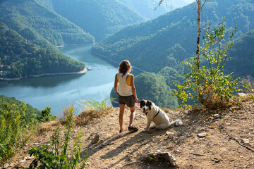 woman and dog on mountain top overlooking a lake