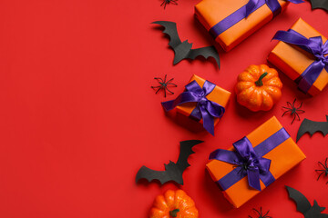Composition with gift boxes, pumpkins and paper bats for Halloween on red background