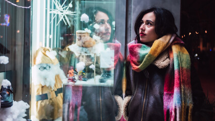 Pretty girl with a scarf looking at Christmas stores
