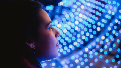 Pretty young girl with scarf admiring the Christmas lights. 