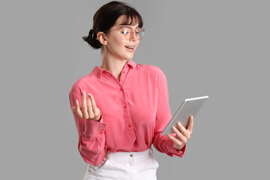 Beautiful businesswoman with tablet computer on grey background