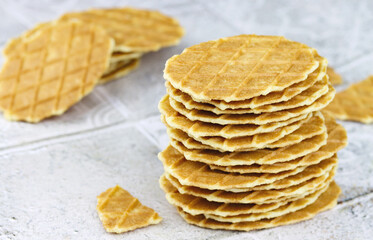 Thin waffles. Stack of home made butter waffle cookies on a grey background. Waffle crisps...