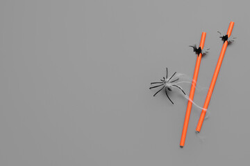 Drinking straws with Halloween decorations on grey background