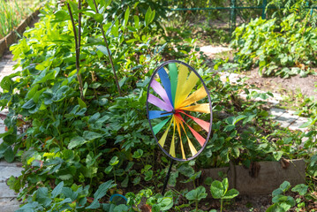 Multi-colored spinner toy rotating in the garden of a cottage colorful wind turbine on a background...