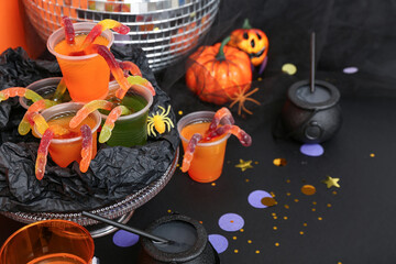 Halloween party composition with punch and gummy worms on black table