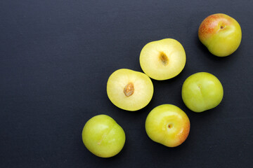 Fresh green plum fruit on dark background.