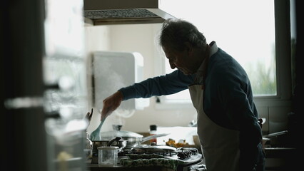 Senior chef preparing food, candid authentic older man close-up hand and face cooking meal by kitchen sink