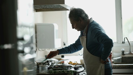 Senior chef preparing food, candid authentic older man close-up hand and face cooking meal by kitchen sink