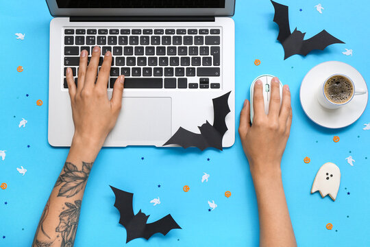 Woman with coffee cup and Halloween decor using laptop on blue background