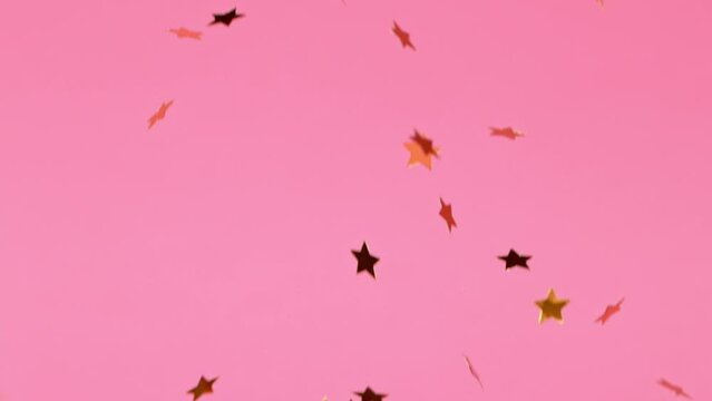 Gold Stars Falling on Pink Background. Super Slow Motion, 1000 FPS.