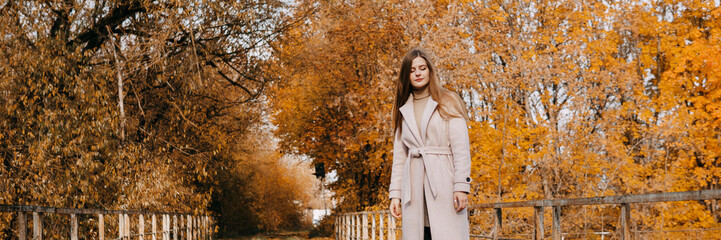 beautiful long-haired woman walks through the autumn streets. Railway, autumn, woman in a coat.