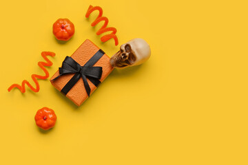 Composition with gift box and Halloween decorations on yellow background