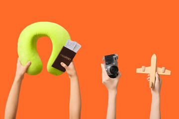 Female hands holding summer accessories on orange background