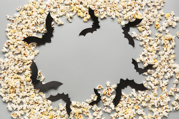 Frame made of tasty popcorn and paper bats for Halloween celebration on grey background