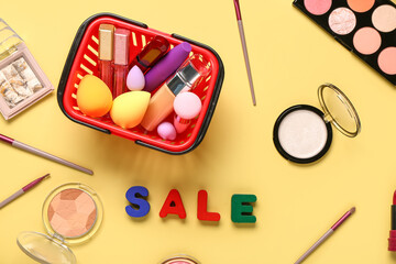 Shopping basket with makeup cosmetics and text SALE on beige background