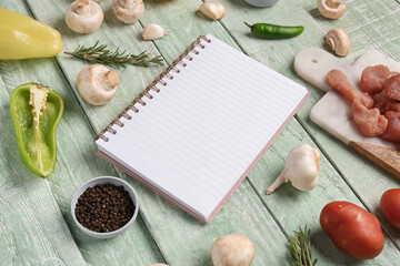 Blank notebook with fresh vegetables on green wooden table