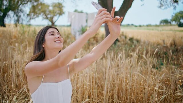 Cheerful girl posing phone camera on rural nature closeup. Woman making selfie