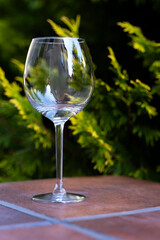 a clear glass wine glass stands on a table in the garden